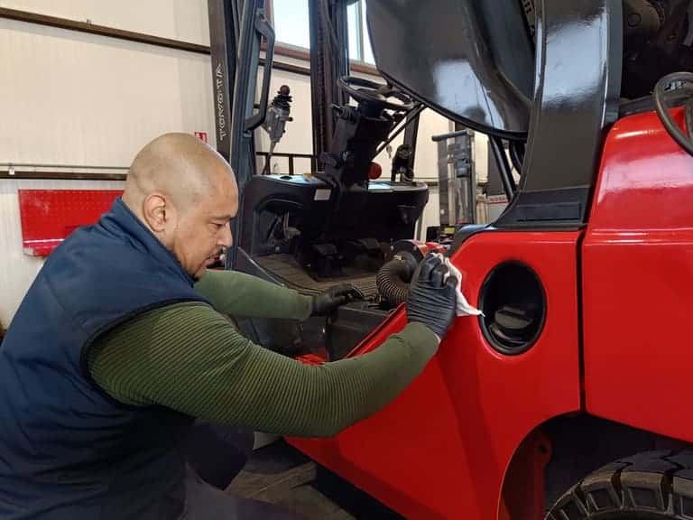 Photo d'un technicien qui entretien un chariot élévateur rouge