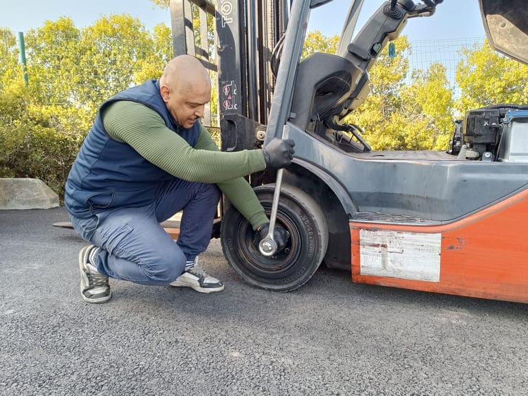 Photo d'un technicien qui réalise le remplacement d'un pneu sur un chariot élévateur